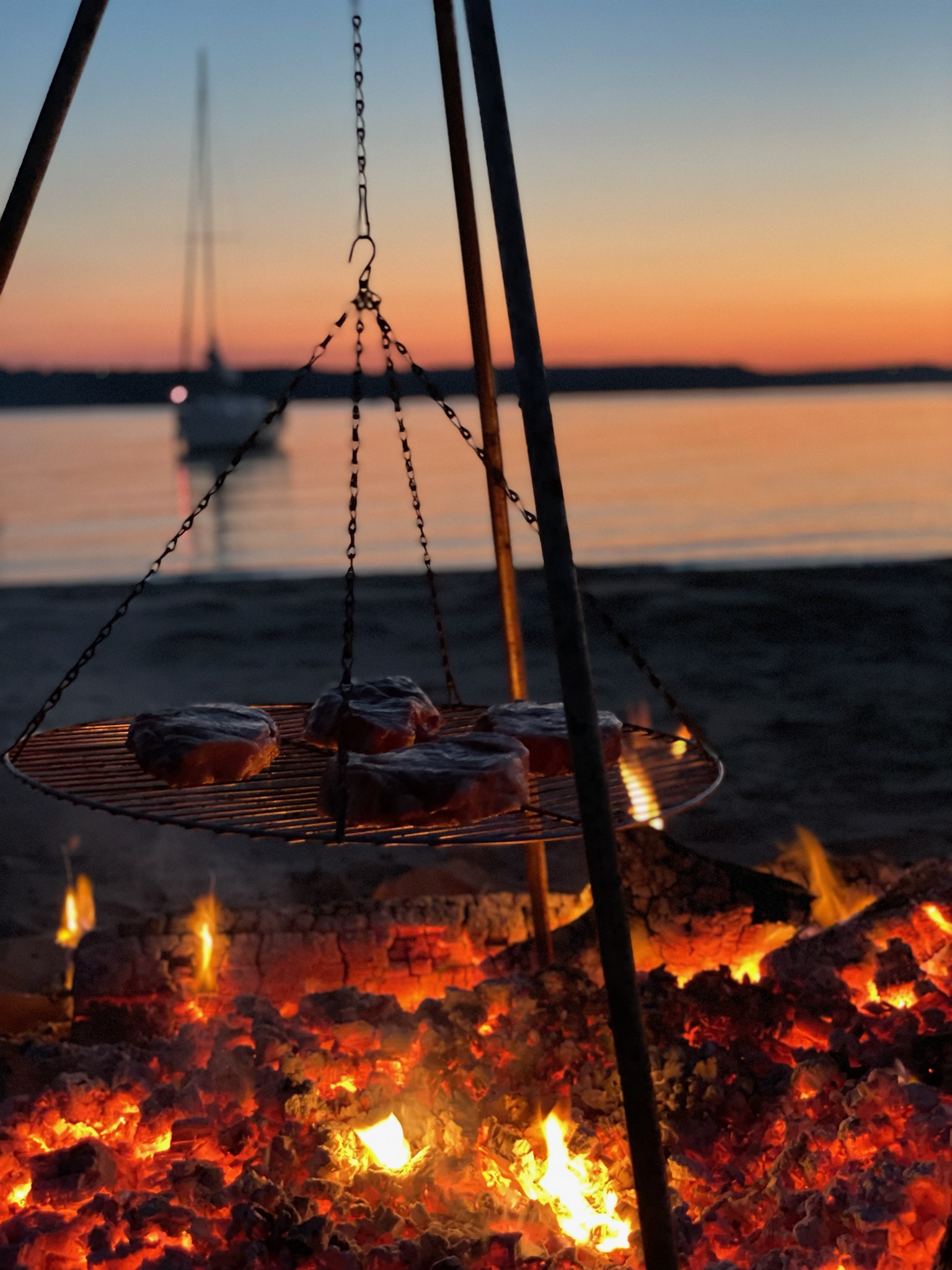 Windycrest members gathered around an evening lakeside bonfire